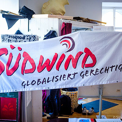Banner mit dem Südwind Logo und den Worten "Globalisiert Gerechtigkeit" 