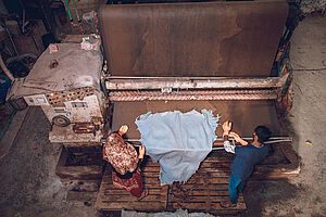 Arbeiter:innen in Bangladesch bedienen eine große Maschine in einer Lederfabrik