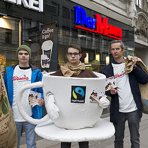 Drei junge Männer bei einer Kampagne für fairen Kaffee. Einer ist als große Kaffeetasse verkleidet