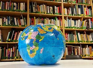 Aufblasbare Weltkugel vor einem Bücherregal in der Bibliothek Salzburg