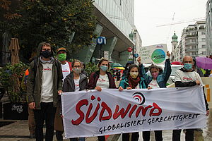 Gruppe von Südwindmitarbeiter:innen hält auf einer  Demonstration Plakate und Transparente hoch