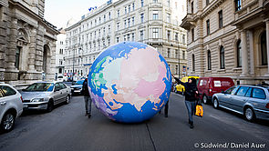 Südwind AktivistInnen beim Rollen einer riesigen Weltkugel durch die Straßen Wiens