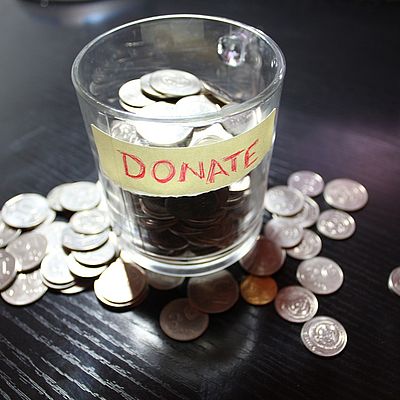 In einem Glas mit der Aufschrift "DONATE" befinden sich einige Münzen 