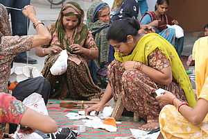 Indische Arbeiterinnen sitzen im Kreis und nähen Fußbälle