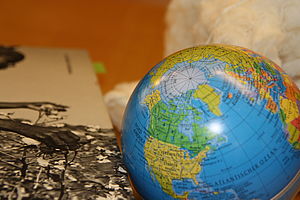 Bild von Baumwolle pflückenden Händen, daneben ein Globus