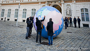 Südwind AktivistInnen mit einer riesigen Weltkugel vor dem Außenministerium, im Hintergrund Polizeibeamte
