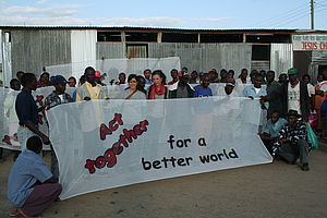 Südwind AktivistInnen und ArbeiterInnen. Dabei ein Banner mit den Worten "Act together. For a better world"