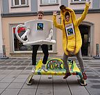 Südwind verkleidet als Fair Trade Kaffeetasse und Fair Trade Banane vor dem Weltladen in Wiener Neustadt