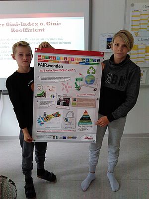 Zwei Schüler halten zusammen ein Plakat bei der Faire-Welt-Ausstellung