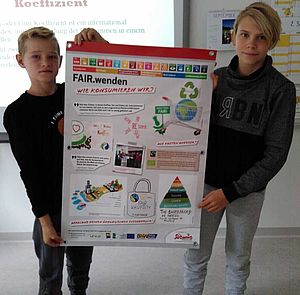 Zwei Schüler halten zusammen ein Plakat bei der Faire-Welt-Ausstellung