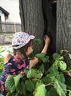 Ein Mädchen findet ein in einem Baum verstecktes Gefäß