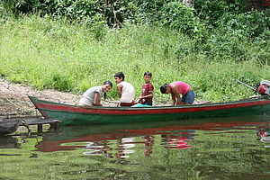 Vier Personen in einem am Steg befestigten Holzboot