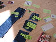 In Teile zerschnittene Jeans liegt auf dem Boden, dabei mehrere Informationskärtchen