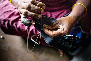 Eine Heimarbeiterin näht einen Schuh in Ambur, Indien