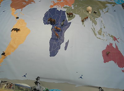 Auf einer Weltkarte sind Figuren von verschiedenen Tieren aufgestellt