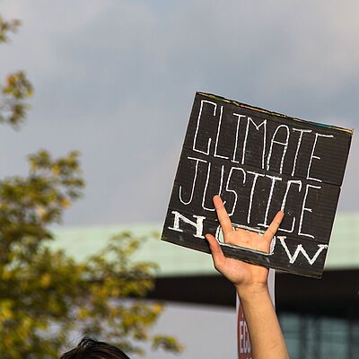 Hand hält Schild mit den Worten "Climate Justice" in die Höhe