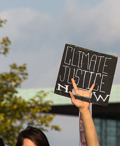 Hand hält Schild mit den Worten "Climate Justice" in die Höhe