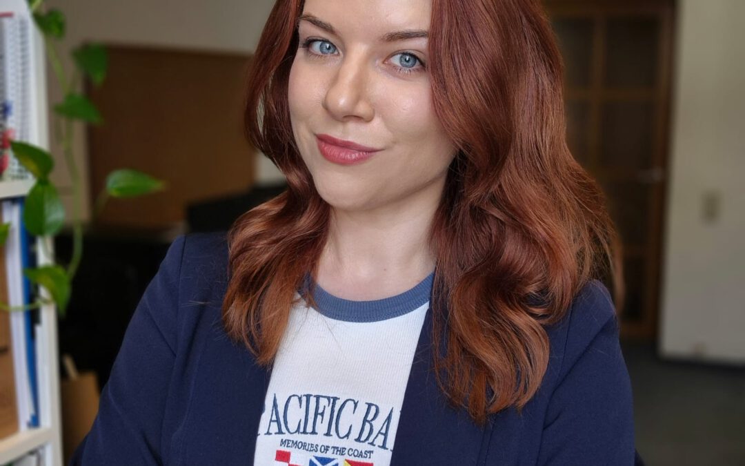 Portraitfoto von Stefanie Marek; Rote offene Haare, blauer Blazer, verschränkte Arme.