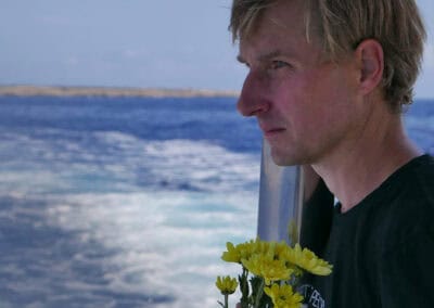 Südwind Mitarbeiter in Lampedusa mit Blumen zum Gedenken an Bootsunglück