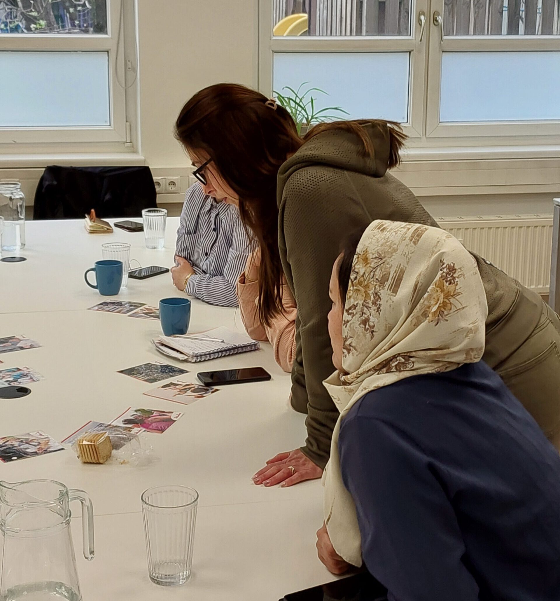 20240407_Training_Civic engagement_Graz_(c) Südwind (6) Zwei Frauen an einem Konferenztisch von der linken Seite aufgenommen. Eine Frau sitzt, die andere steht.