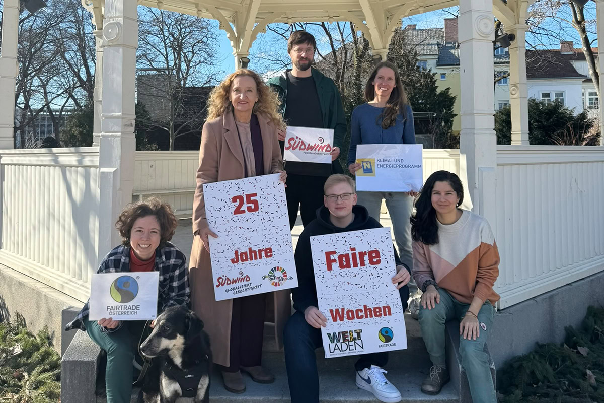 Faire-Wochen_c_Suedwind Vier Frauen, zwei Männer und ein Hund sind gut gelaunt im Freien vor einem Pavillion bei sonnigem Wetter zu sehen.